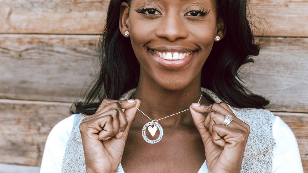 Model wearing jewelry for moms with children's names and a heart charm